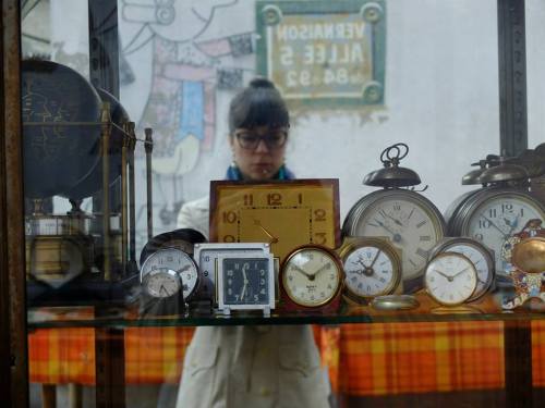A self-portrait of the author taken in a mirror. A half-dozen old alarm clocks are in the foreground.